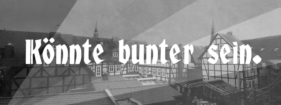 Eine schwarz-weiße Ansicht von Salzwedeler Fachwerkhäusern. Darauf in weißen Buchstaben der Satz: Könnte bunter sein.