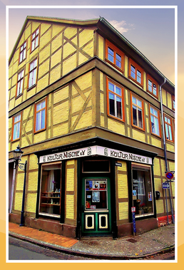 Eingang der Kultur-Nische an der Ecke Radestraße und Neutorstraße in Salzwedel. Man sieht den Eckeingang eines hellgrünen Fachwerkhauses mit insgesamt vier Geschossen.