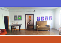 Ansicht von einem Raum in der Kultur-Nische. in der Mitte eine offene Tür, am rechten Bildrand ein Sofa, an den Wänden hängen Bilder.